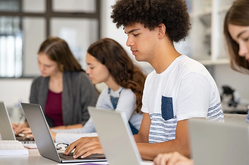 students sitting at table using laptops