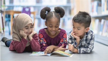 Learning with Confidence: Three children smile as they read a book together.