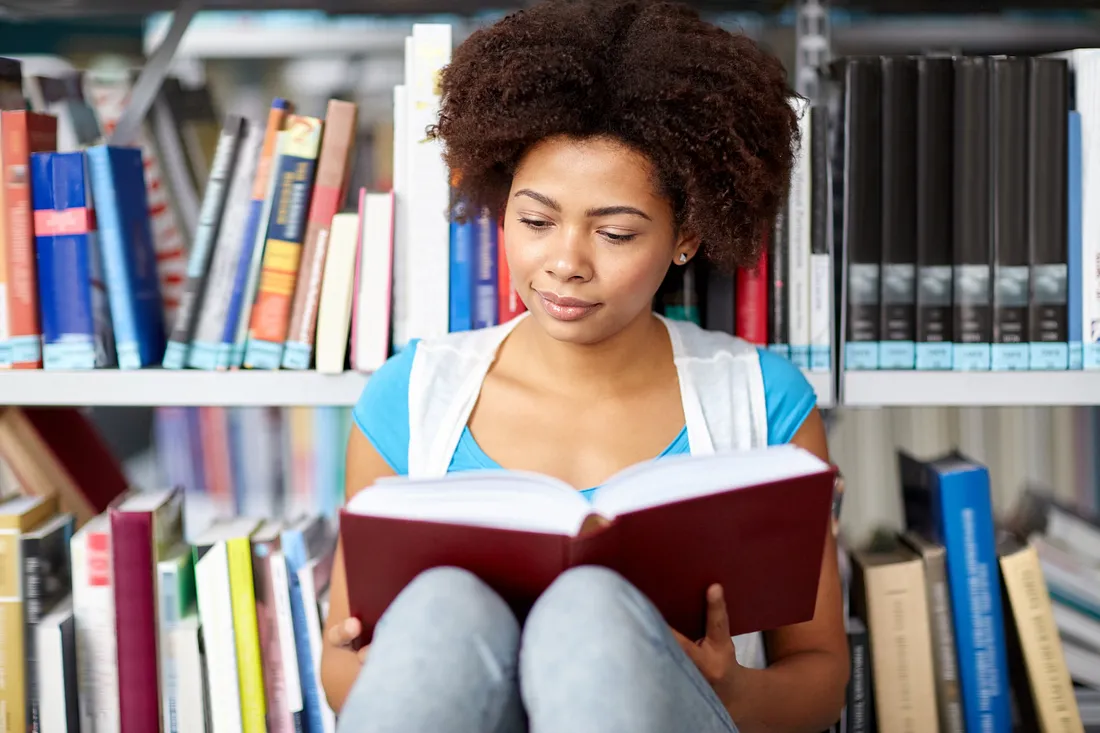 student in library reading a book