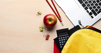 apple and backpack sitting by laptop